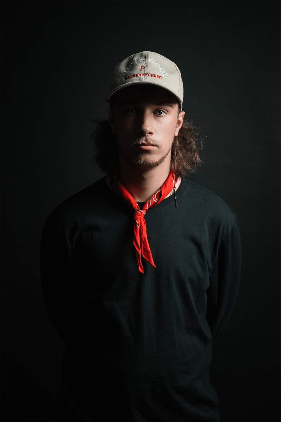 Young man with long hair wearing a beige cap and red bandana