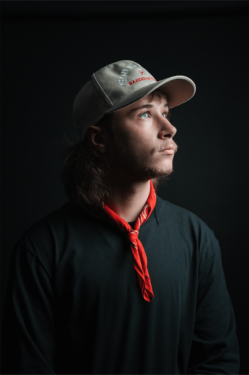 A young man wearing a jacket looking up above